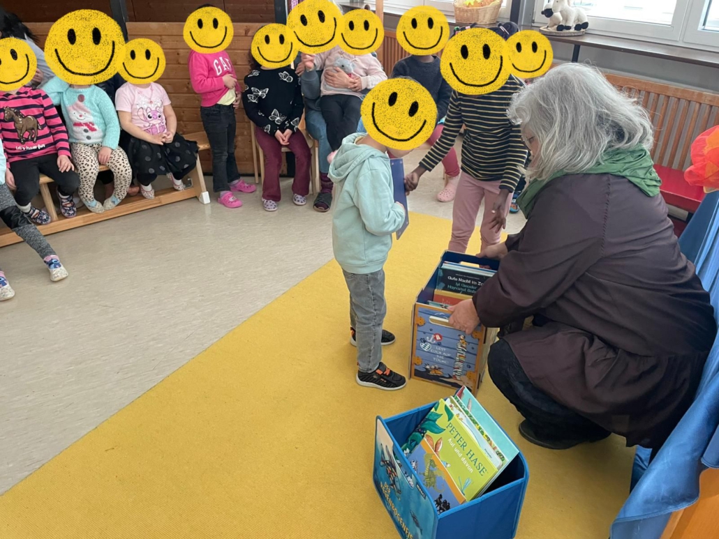 Kitakinder schauen in eine Kiste mit Büchern